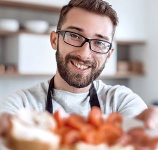 一个有魅力的男人手里的三明治 夹在一个漂亮的男人手中眼镜营养围裙男性小吃丈夫桌子美食熏肉食物图片