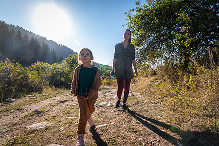 一个年轻母亲和她女儿5岁的女儿在山上散步 女孩像马一样用棍棒子图片
