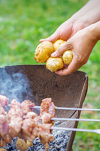 男人准备烧烤肉和土豆食物自助餐餐饮火盆团体炙烤鱼片牛肉野餐街道图片