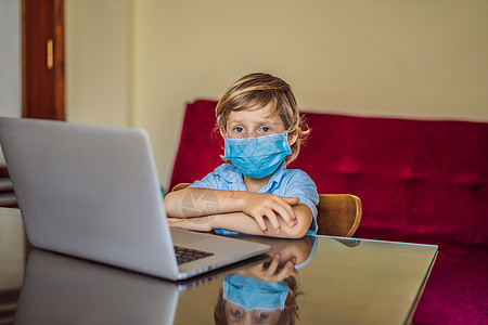 使用医疗面具的膝上型笔记本电脑在家中在线学习的男孩 以保护他们免受冠状病毒的侵害 在隔离期间进行研究互联网消毒剂喜悦家庭作业父亲图片