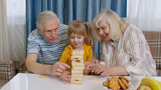 外祖父母和孩子孙女孙女在家中用木砖玩游戏的幼童图片