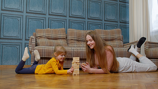 快乐的年轻母亲 在家中教小女儿玩木砖板游戏(木块板游戏)图片