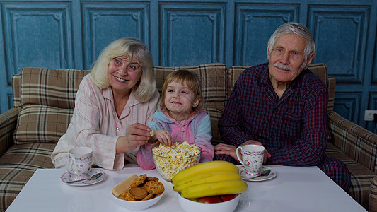 祖父母在电视上看卡通电影 外孙女在家欢笑快乐的笑着图片