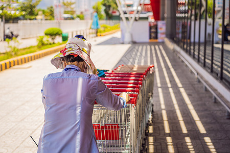 女员工在连锁超市分店外收集购物手推车图片