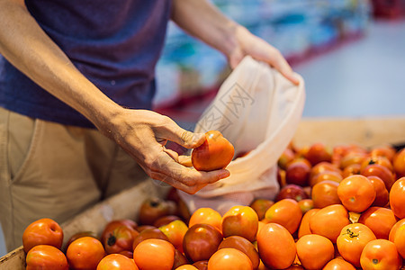男人在超市中选择番茄而不使用塑料袋 购买蔬菜的可再用袋 零废物概念环境塑料回收水果大部分农贸市场织物购物食物棉布图片