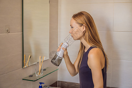 妇女在浴室使用口服喷水器牙刷刷子牙线长发灌溉镜子配饰灌水器治疗牙科图片