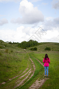 穿粉红色雨衣的女人看着山路 在山上徒步旅行 出行 户外娱乐的概念图片