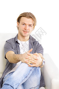 坐在客厅沙发上 微笑着的相机上的快乐青年男子的肖像图片