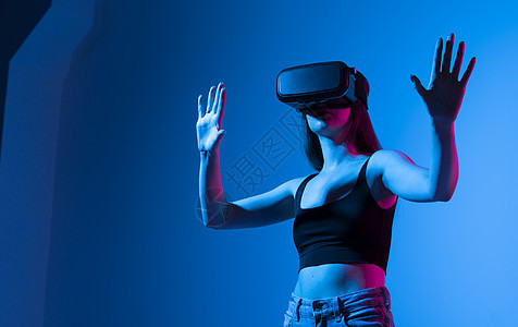 快乐的女孩手举起来 戴着虚拟现实眼镜 玩着明灯游戏 未来技术概念 新颖的概念 笑声头盔高科技创新模拟虚拟性电脑乐趣风镜宇宙工具图片