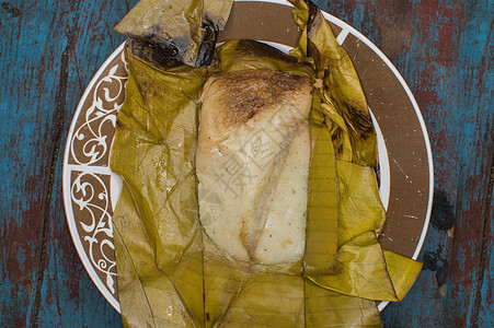 木制餐桌 香蕉叶上塞满的塔马人 木制餐桌 典型的尼卡拉瓜食品烹饪盘子玉米面包早餐美食蒸肉叶子食物背景图片