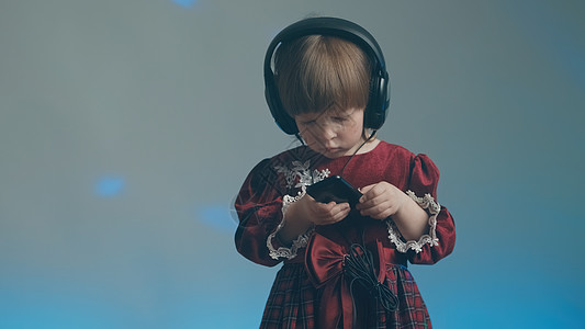 穿着大耳机和古代礼服的小女孩 在电话里听音乐复古衣服乐器蓝色婴儿玩家裙子宝宝长袍工具图片