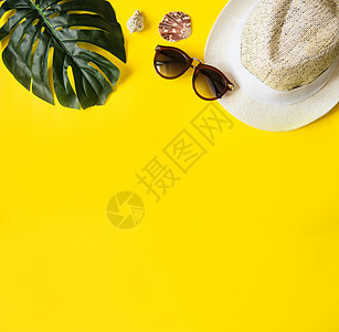 黄色背景上的海滩配饰  太阳镜和条纹帽子 夏天即将到来的概念 热带叶龟背竹 夏季平躺 顶视图 文本空间叶子框架旅行眼镜太阳配件情图片