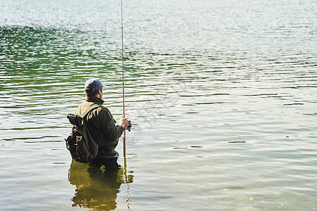 渔民站在水中 在湖里钓鱼 在山的深山背景上男人帽子日出假期运动纺纱垂钓者天空溪流活动图片