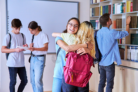 学生抱抱在会议上的女生 学校图书馆里的青少年群体 (校内)图片