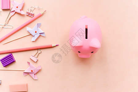 学校购物概念 粉红色背景的文具和小猪银行图片