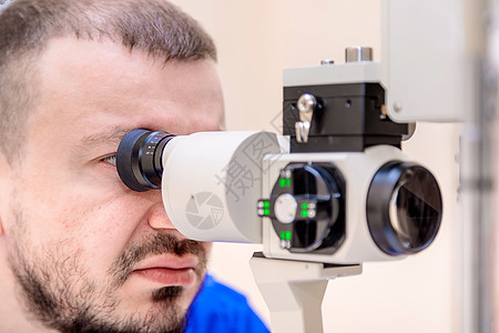 男性眼科医生用现代设备 光束和光束检查病人的视力图片