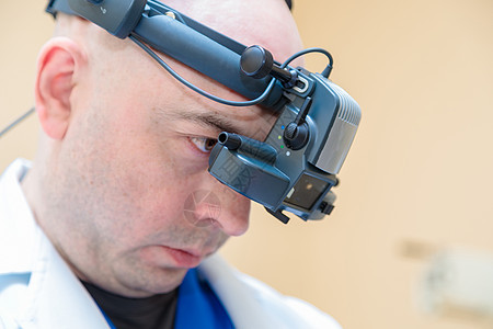 男性眼科医生用双目眼透镜检查病人的视力 以检查患者的视力眼睛配镜师眼力验光乐器测量眼镜头盔测试考试图片
