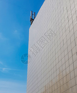 现代商业型建筑的外墙 用瓷砖围在屋顶上 现代天线对着蓝色天空与蓝天相对办公室摩天大楼玻璃窗户控制板活动对角线绘画贸易床单图片