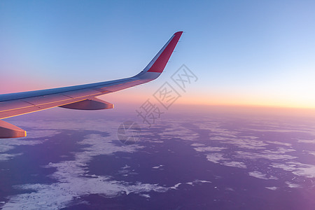 飞机的机翼和地面通过照明器观察到 在空中飞行日落乘客运输速度飞机场舷窗航空高度房屋阳光图片