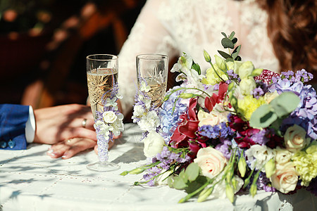 在新郎和新娘的拥抱背景下 在花园里装饰了桌布 以鲜花 花卉配制为风格的婚礼装饰品图片