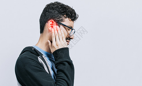 耳炎和耳鸣患者的概念 耳朵疼痛的人 在孤立的背景下 受苦的人按摩他的耳朵孤立图片