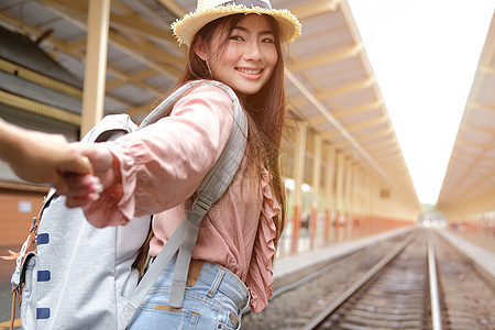 男人和女人背着背包手牵着手在火车站等火车 恩爱的情侣旅行者一起旅行图片