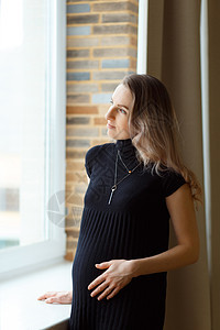 深思熟虑的孕妇抚摸她的肚子女性幸福母性父母房间怀孕成人家庭窗户孩子图片