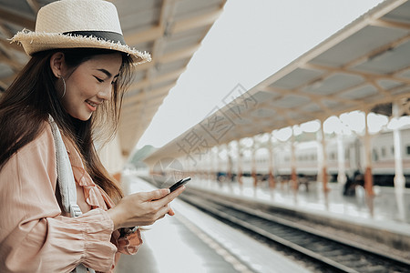 背包里的女旅客在火车站使用智能手机 旅行旅行旅行概念技术铁路乘客火车女士女性民众运输车站电话图片