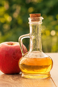 玻璃瓶中的苹果醋和木板上新鲜的红苹果乡村果汁水果食物玻璃桌子绿色红色液体瓶子图片