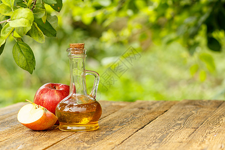 玻璃瓶中的苹果醋和木板上新鲜的红苹果水果食物液体果汁乡村玻璃绿色红色瓶子桌子图片