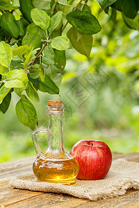 玻璃瓶中的苹果醋和木板上新鲜的红苹果果汁食物红色桌子绿色玻璃瓶子液体水果乡村图片