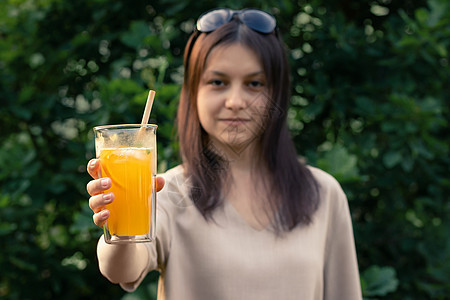 美丽的女孩拿着一杯杯子 配着新鲜的橙色夏季鸡尾酒 有选择性的焦点图片