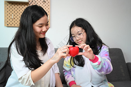 微笑的亚洲女孩穿着医疗制服假装是医生在家里和她的妹妹一起玩图片