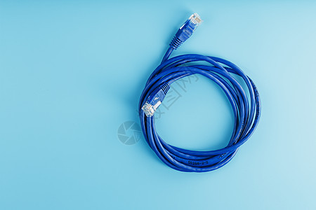 蓝色背景上用于数据传输的互联网网络电缆线圈宽带局域网连接器金属电脑绳索电话架子速度宏观图片