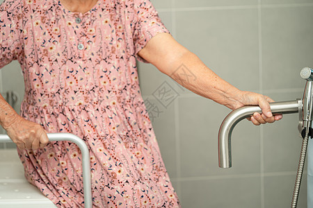 亚洲老年或老年老妇人病人在护理医院病房使用厕所浴室手柄安全 健康强大的医疗理念洗手间淋浴金属铁轨潮红座位旅馆减值医院扶手图片