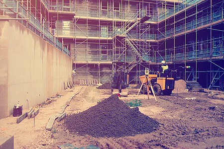建造者在新建筑施工现场驾驶自卸车和挖掘机 施工现场测量设备图片
