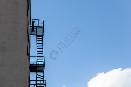蓝天对面高楼大楼的火灾逃生梯的休全月天空蓝色金属街道安全楼梯建筑砖墙窗户出口图片