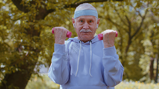 夫妻老人年长男子在公园锻炼 做哑铃举重运动 参加体育训练和有氧运动力量动机休闲哑铃爱好男人体操老人治疗背景