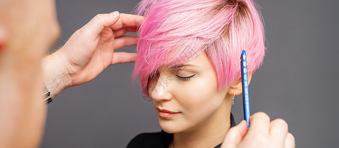 发型师检查女人的粉色发型梳子工作室美容师女性头发理发女孩沙龙工作职业图片