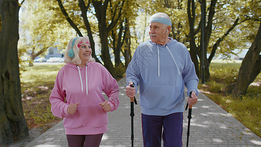 活跃的高级祖父母培训北欧人步行滑雪 在夏季公园跑动 在冬季公园运行远足活力训练祖母退休运动员家庭行动老年娱乐背景图片