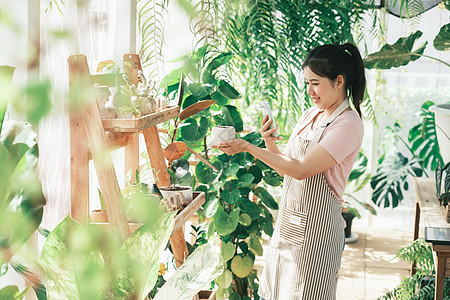 微笑的年轻女子拍摄小商店植物的智能手机照片 在商务企业家农业人士中心销售园艺技术店铺商业图片