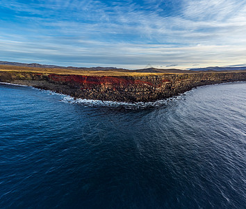 冰岛有红色接缝的坚固悬崖 从海洋看图片