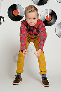 复古迪斯科 60 年代 70 年代 80 年代的概念 风趣的男孩穿着格子衬衫 背景上有音乐盘子的时尚发型图片
