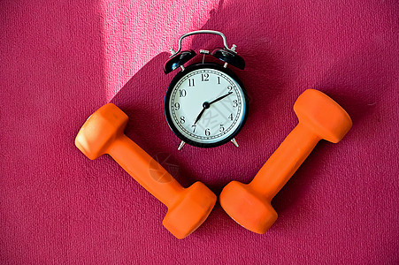 两条橙色隧道和一张粉红色瑜伽垫上的闹钟 该用设备在家健身了 检疫体育纪律力量减肥健身房警报腹肌工具培训师瑜伽重量身体图片