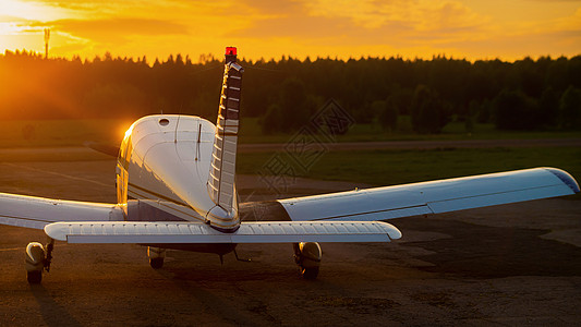 四轮式飞机停在私人机场 看到日落背景有螺旋桨的飞机后视线航天齿轮自由天气尾巴航空机身空气旅行吹笛者图片