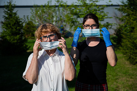 妈妈和女儿戴上医用口罩以防止感染传播 两名老年和中年妇女受到保护免受冠状病毒感染女性症状家庭街道药品流感安全手套风险福利图片