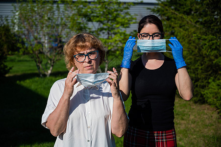 妈妈和女儿戴上医用口罩以防止感染传播 两名老年和中年妇女受到保护免受冠状病毒感染疾病战略手套细菌风险女士面具隔离卫生社交图片