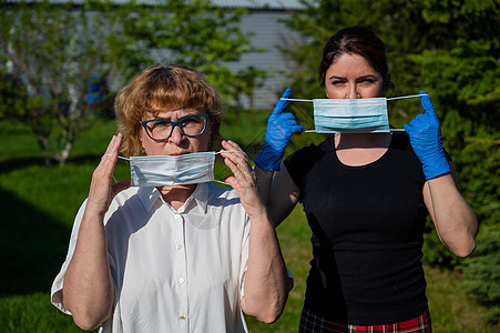 妈妈和女儿戴上医用口罩以防止感染传播 两名老年和中年妇女受到保护免受冠状病毒感染疾病细菌面具手套传染性街道战略女性公园流感图片