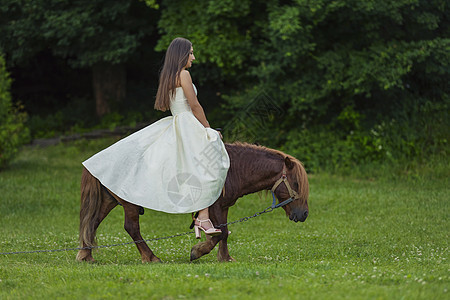 穿着白裙子的女孩骑着小马马背幸福牧场女士帽子娱乐农村农场马术场地图片