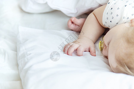 婴儿睡在白床上 有选择的焦点男生就寝眼睛新生白色时间儿童水平童年说谎图片